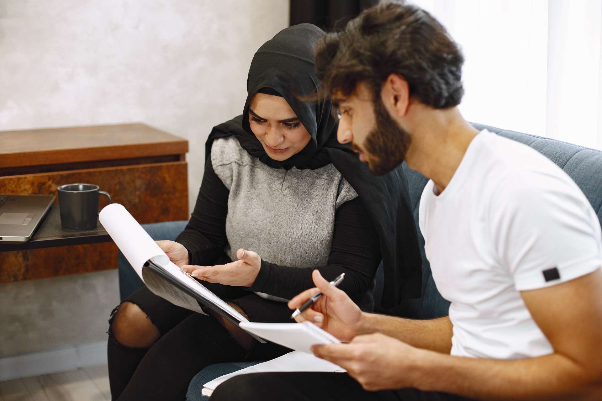 beautiful-young-couple-writing-notebook-sitting-couck-home-arab-girl-wearing-black-hidjab (1)